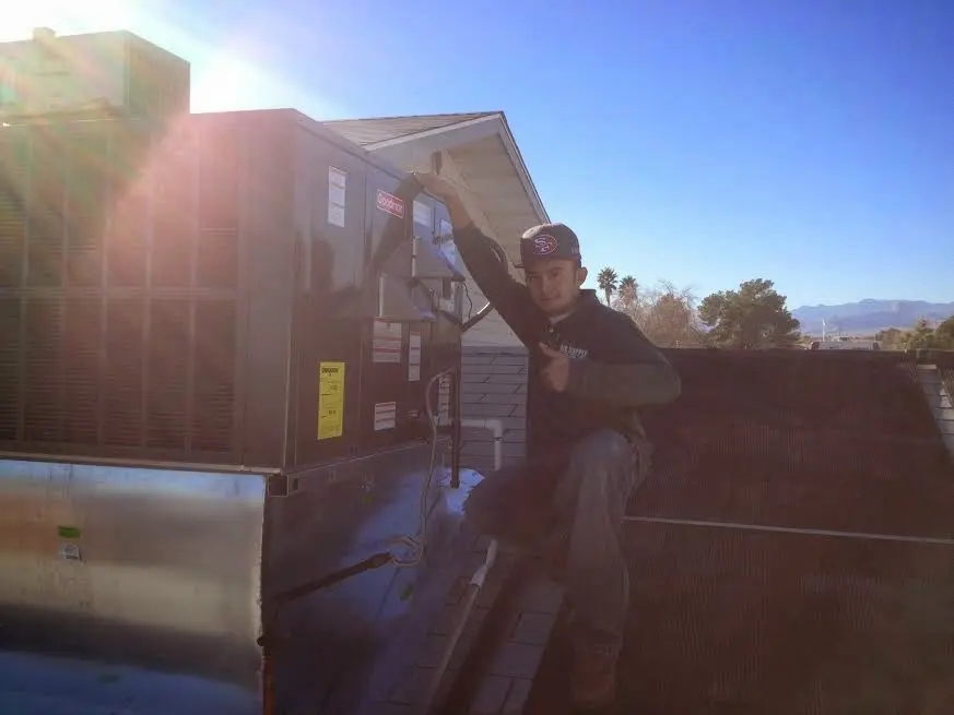 HVAC technician performing Heat Pump Repair on a rooftop unit in Spring Creek